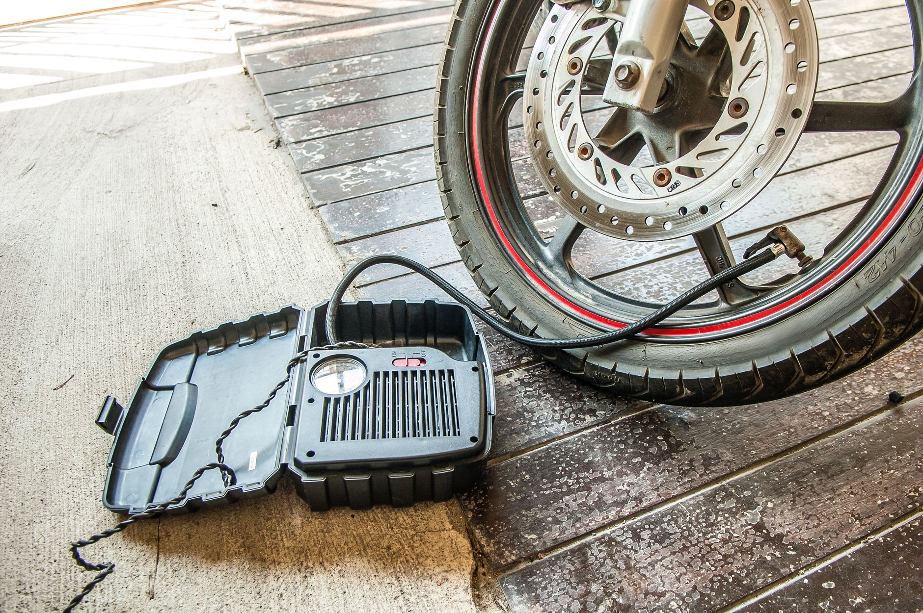 A portable inflator next to a motorcycle tire