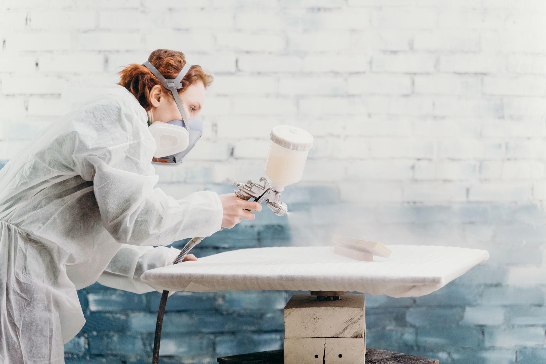 A woman spray painting in protective gear
