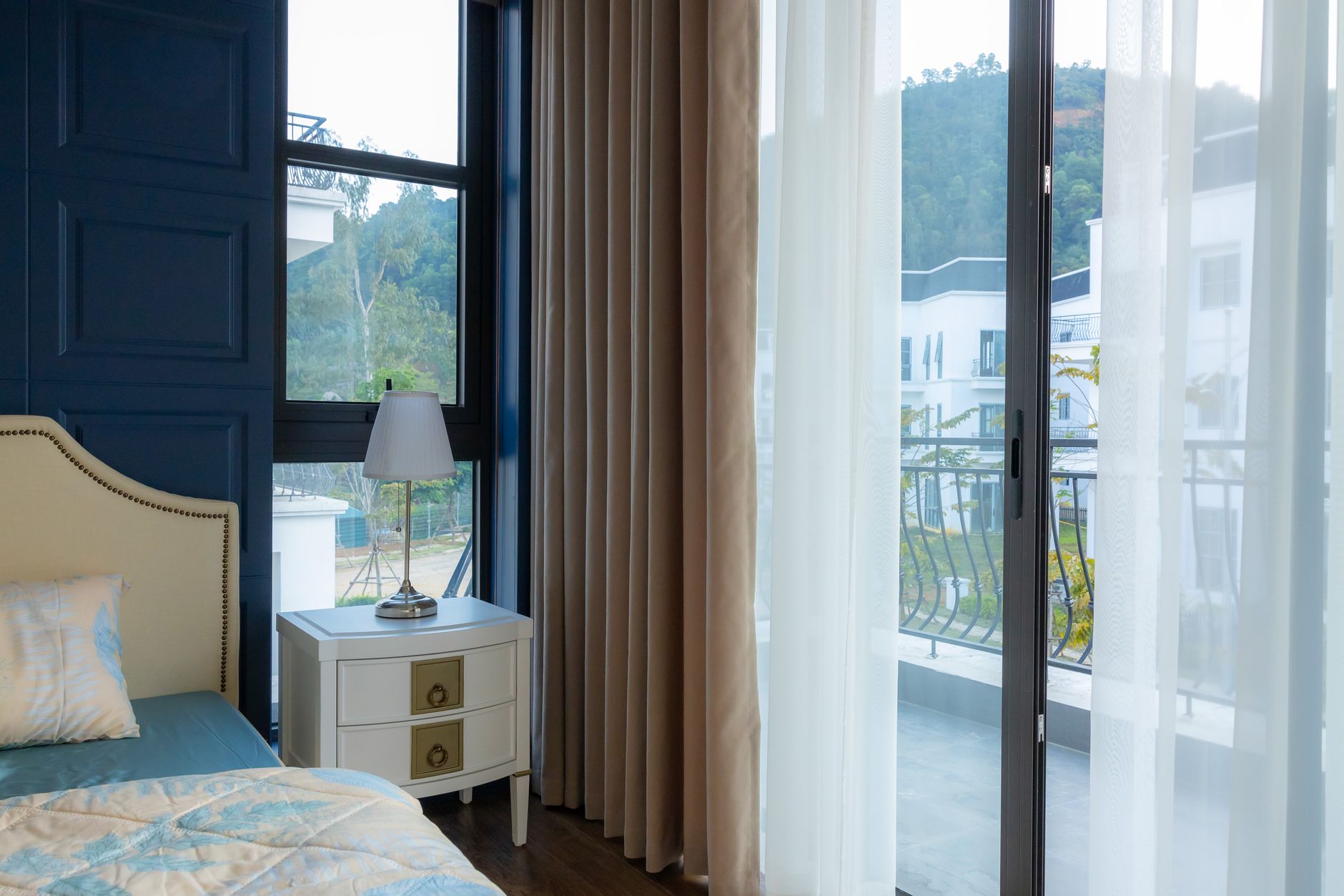 A bedroom with a balcony door and sheer curtains