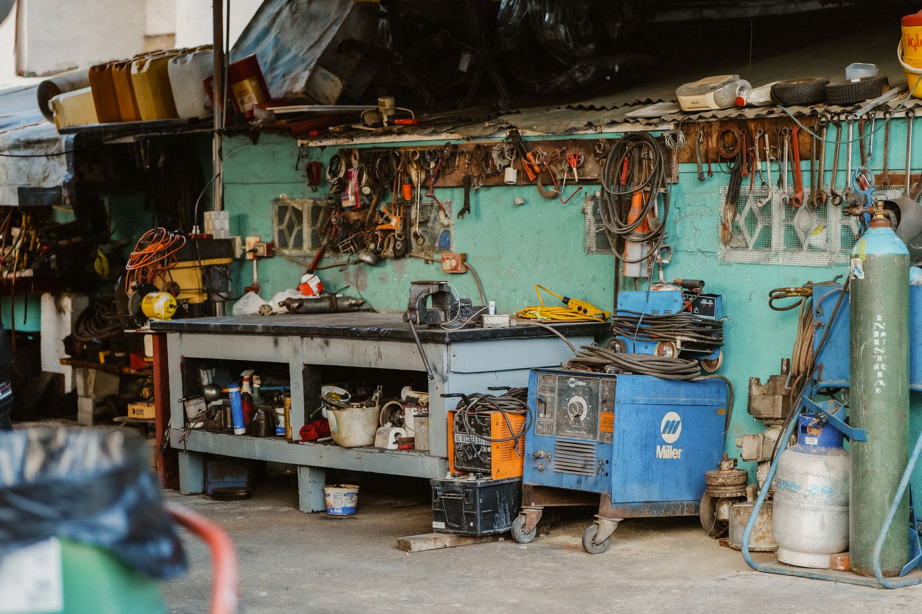 A cluttered workshop bench with tools and gas cylinders