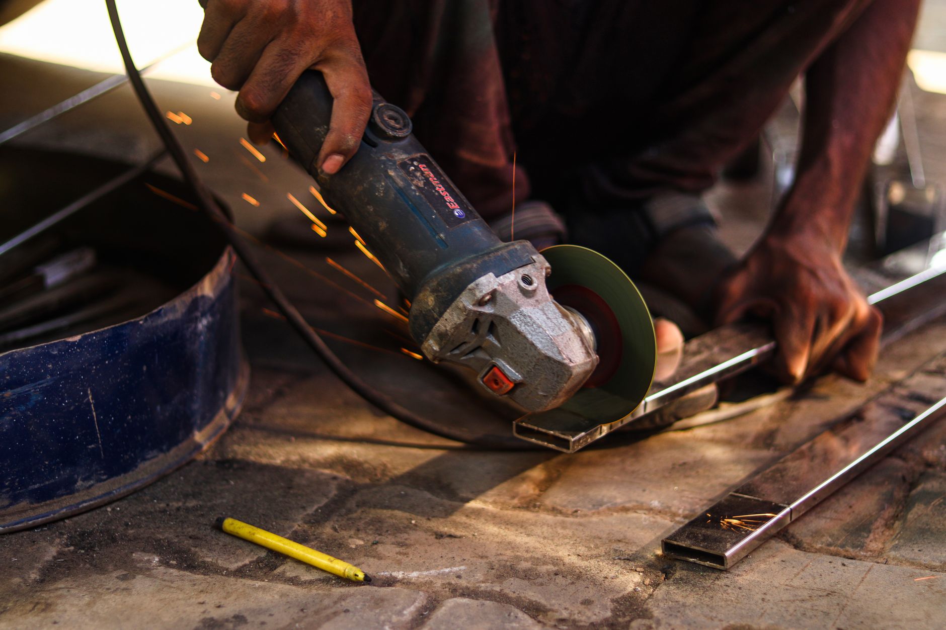 An angle grinder cutting a metal bar