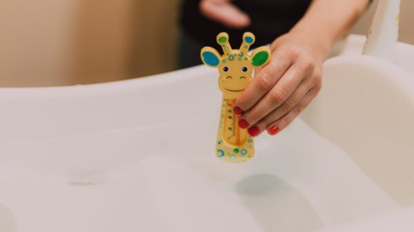Best baby bathtub: a parent checking bath water with a toy thermometer