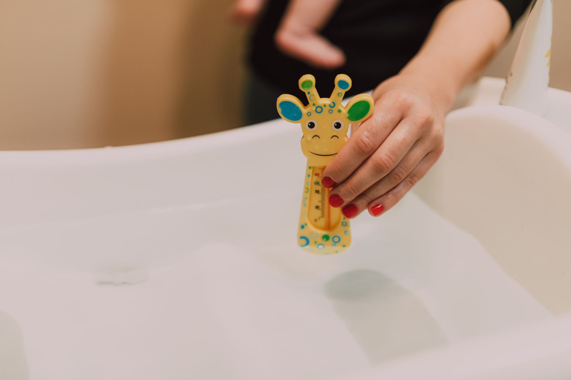 Best baby bathtub: a parent checking bath water with a toy thermometer