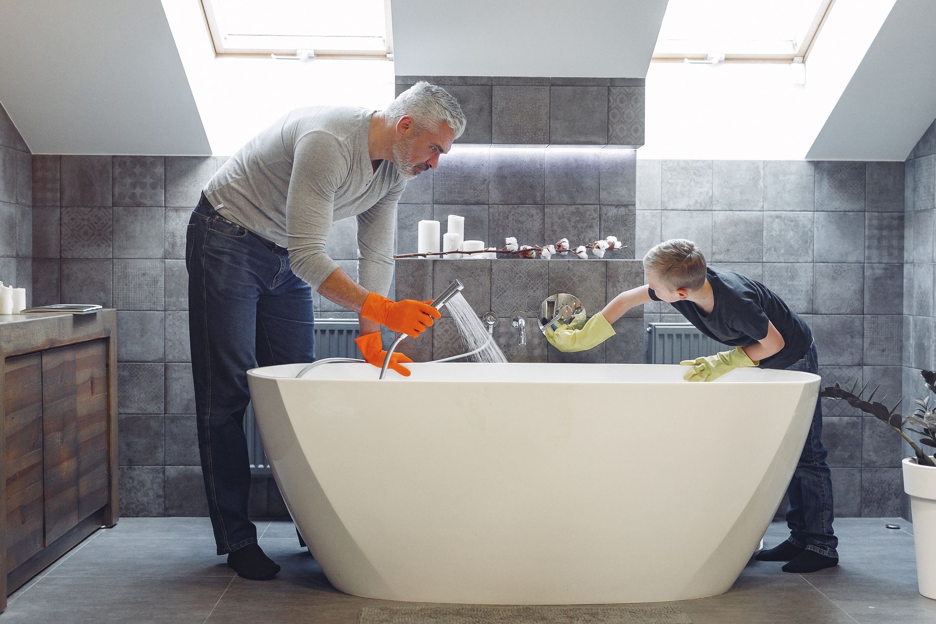 A father and child cleaning a freestanding tub