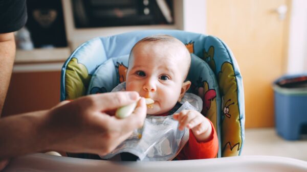 Best baby food maker: a baby being spoon-fed in a high chair