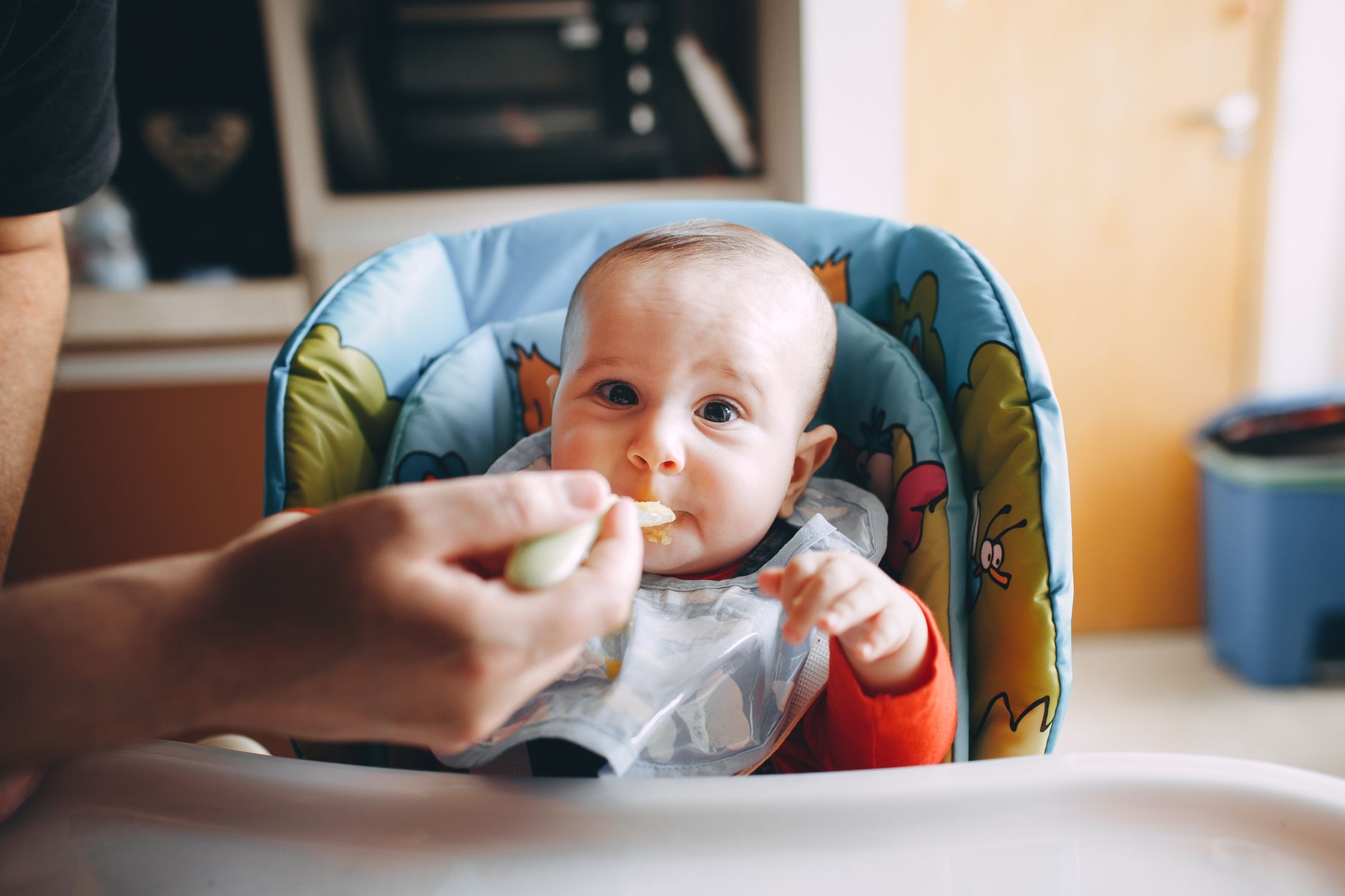 Best baby food maker: a baby being spoon-fed in a high chair