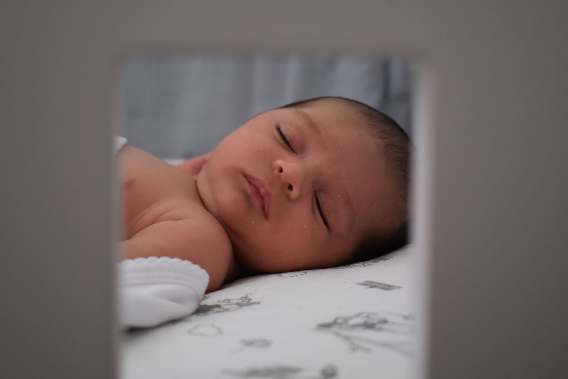 A sleeping newborn seen through a frame