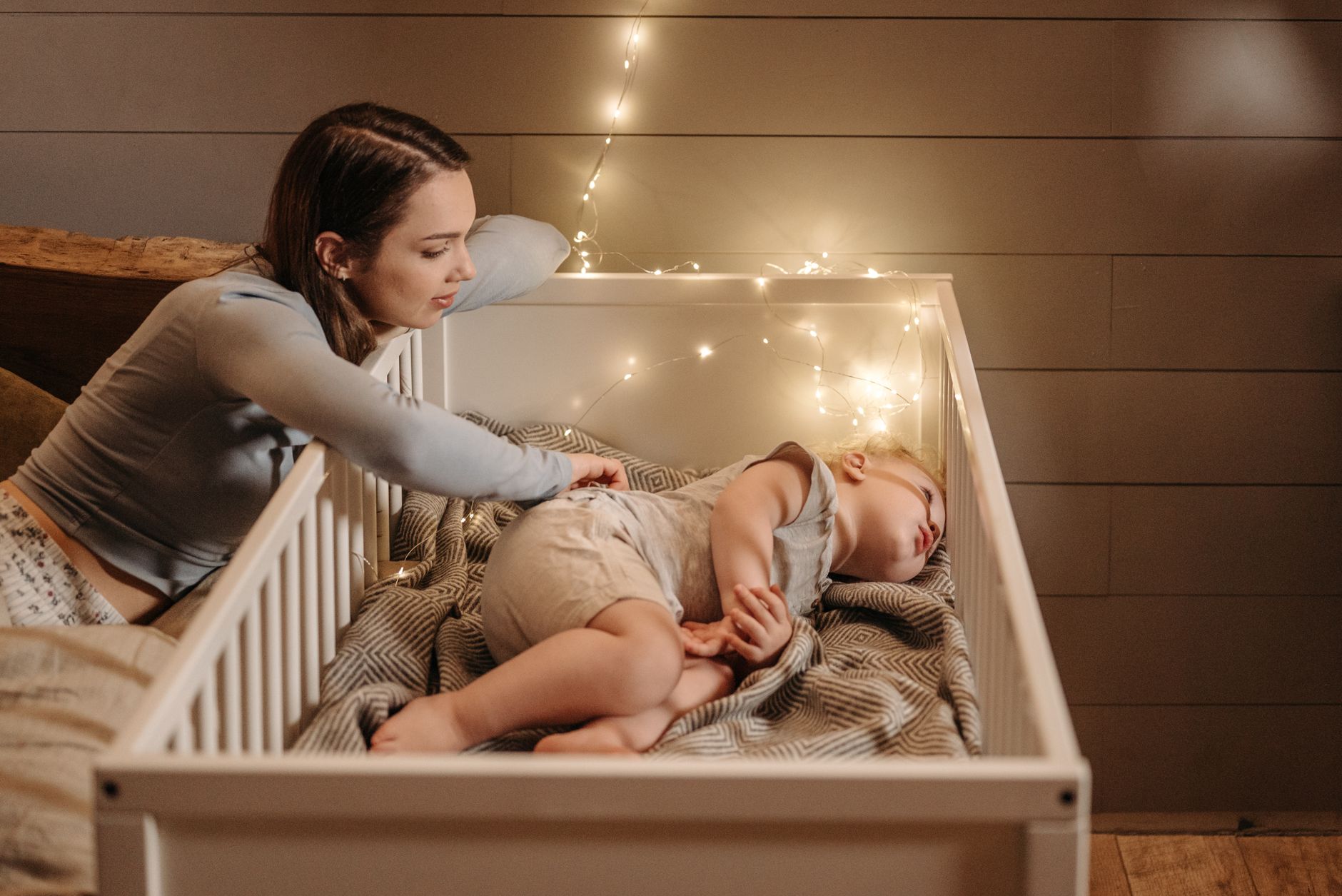 A parent checking on a baby in a crib