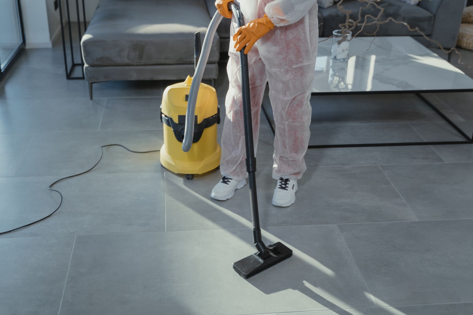 Best backpack vacuum: a worker in protective gear vacuuming a tile floor