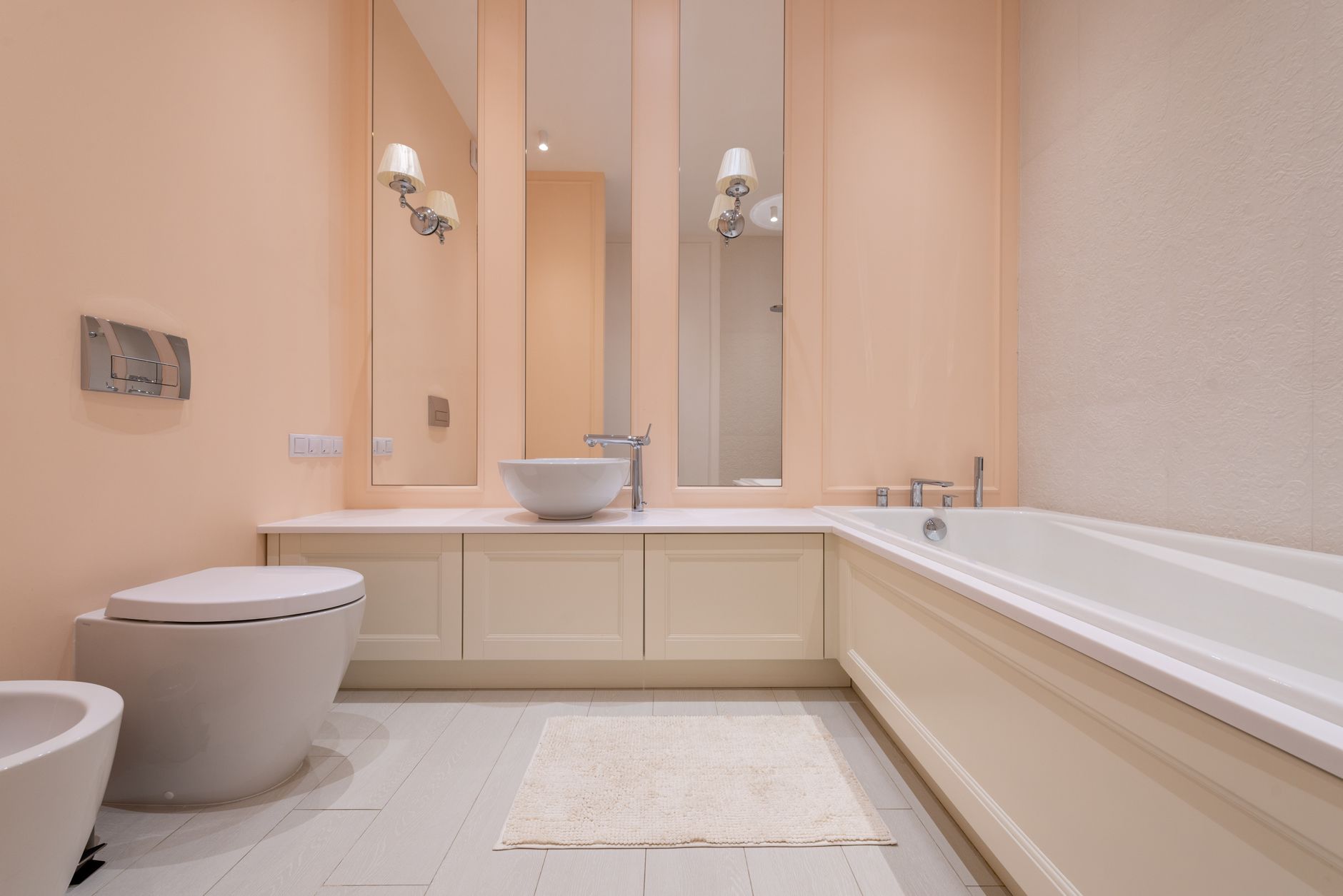 A bath mat on the floor of a peach-toned bathroom