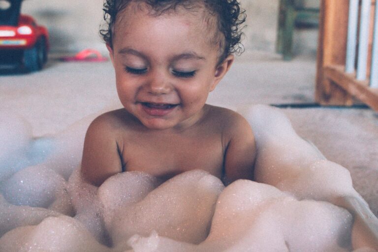Best bath toys: a smiling toddler in a bubble bath