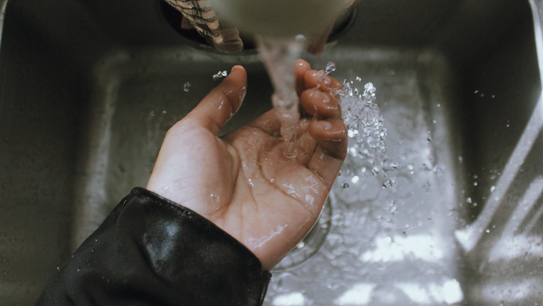 A hand under water running into a sink
