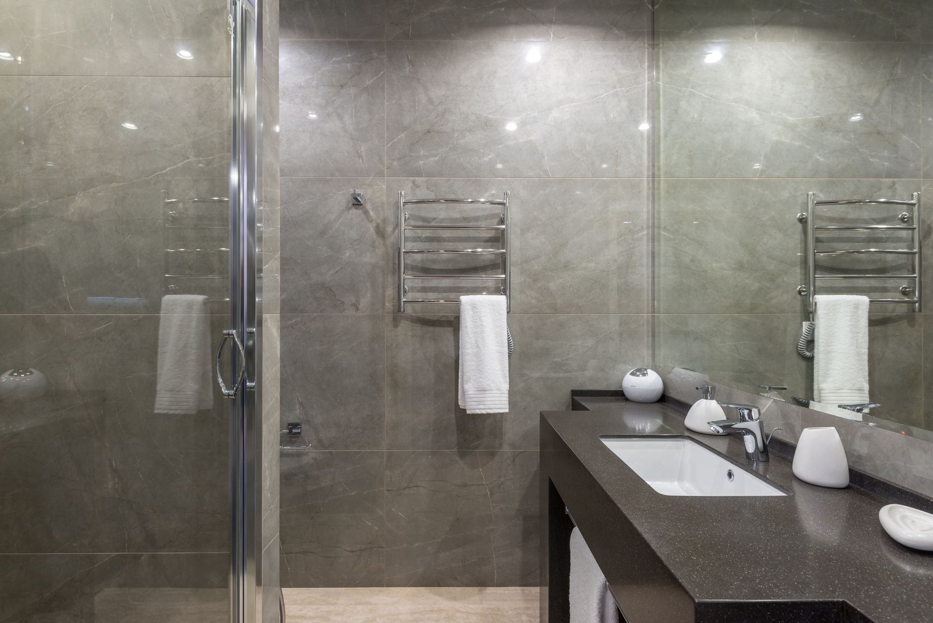 A gray bathroom with a glass shower and heated towel rail