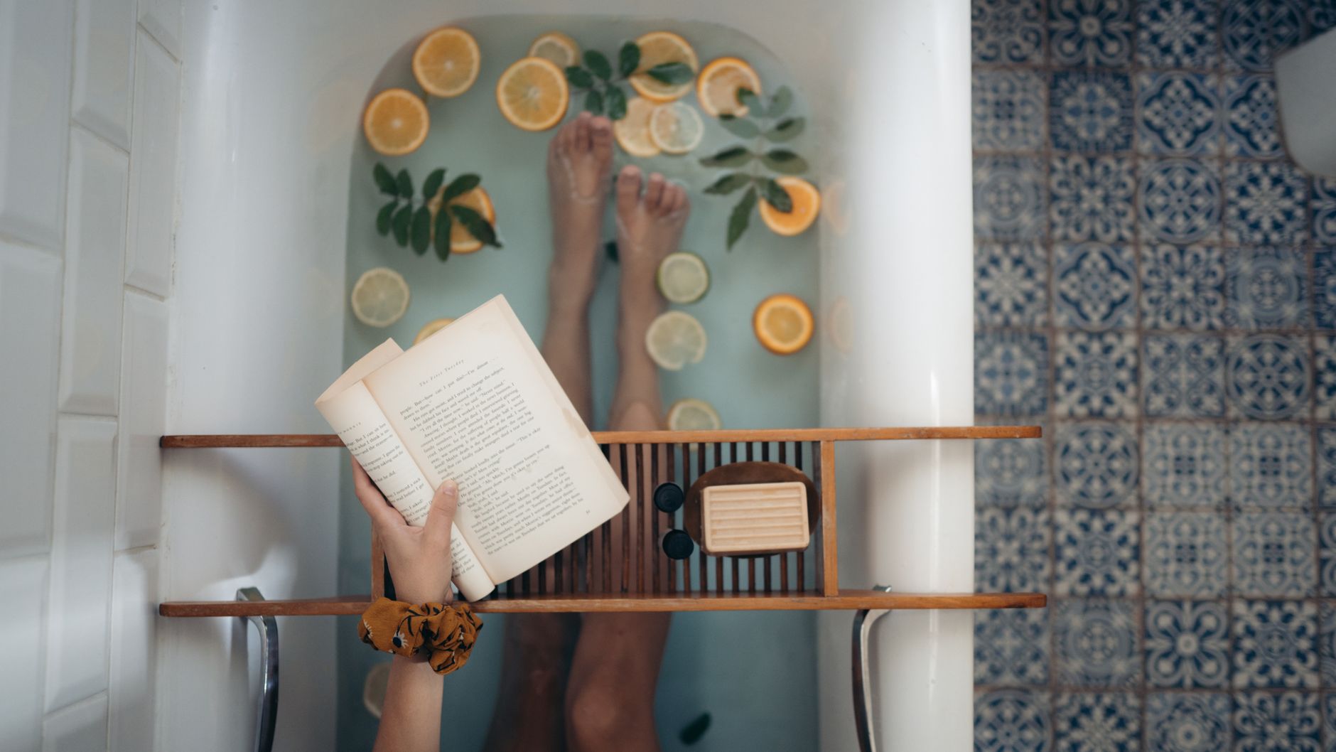 An open book on a bath tray over a tub