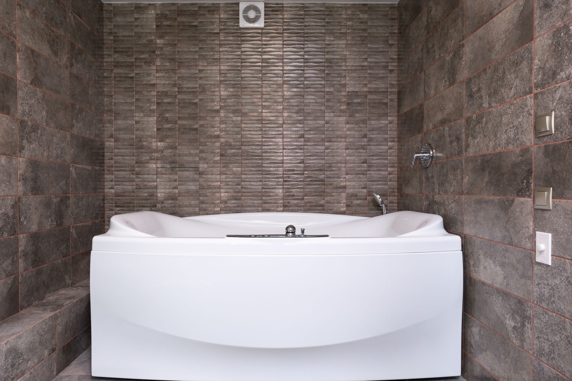 A tub set in a dark tiled alcove