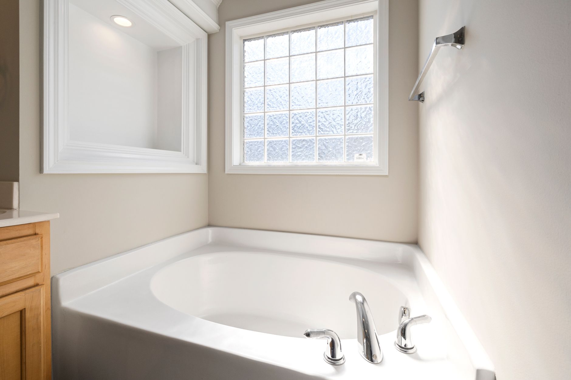 A corner tub below a glass-block window