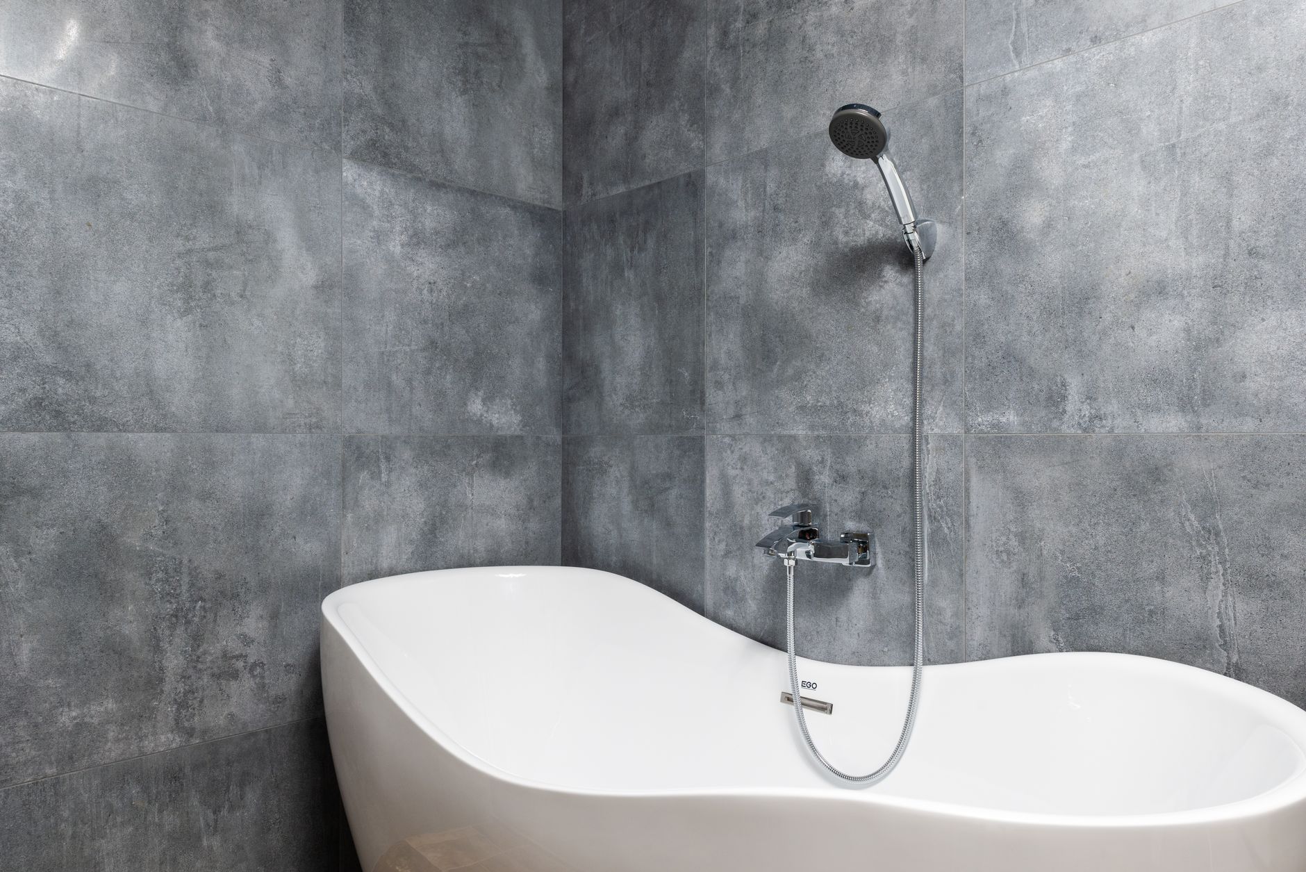A freestanding tub in a gray tiled bathroom
