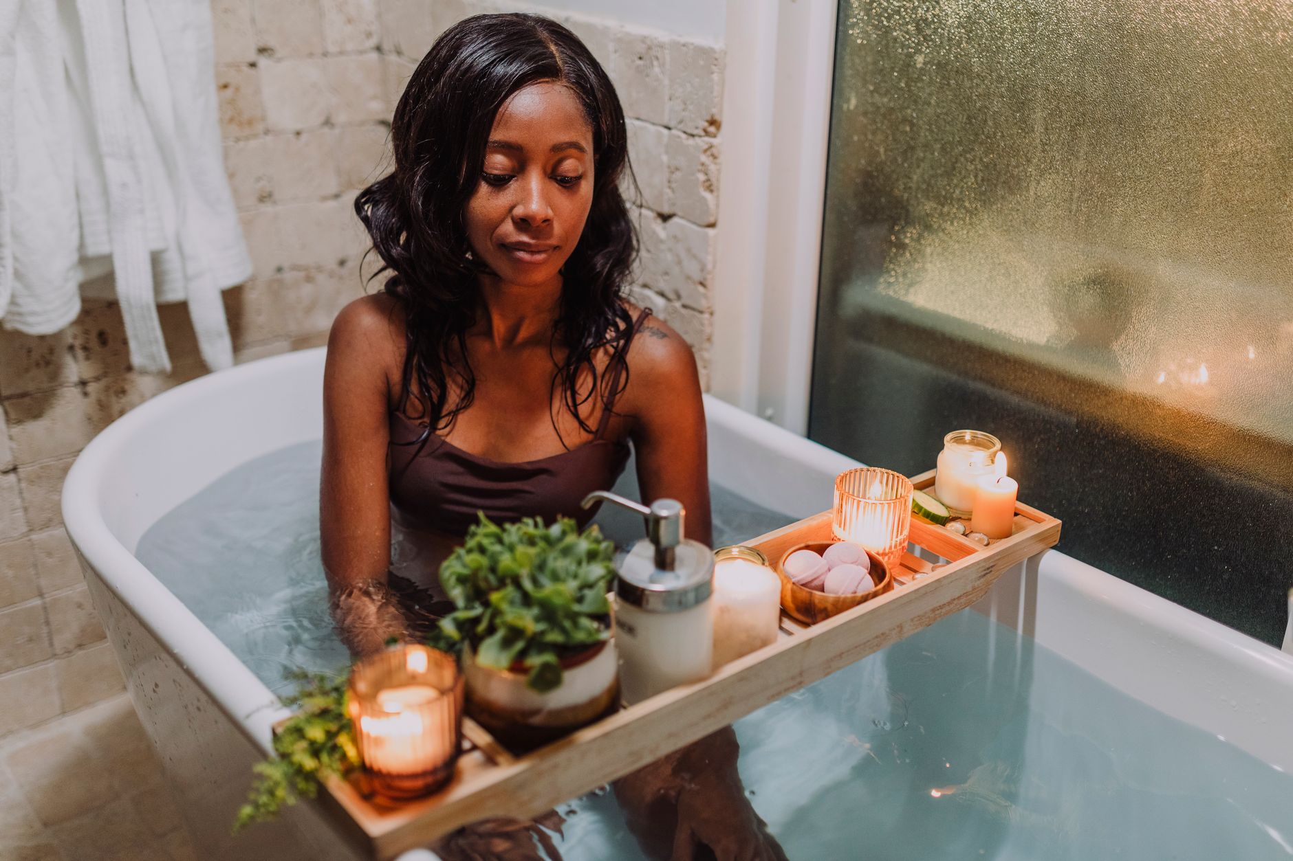 A woman relaxing in a bath with candles