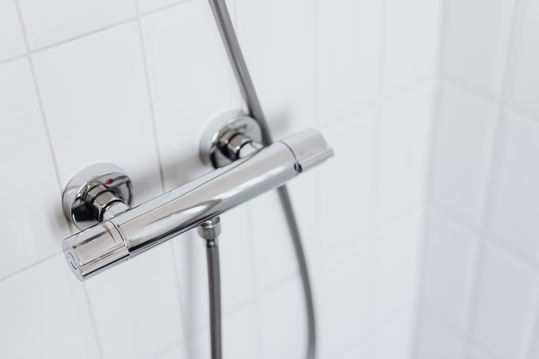 A chrome shower valve on a tiled wall