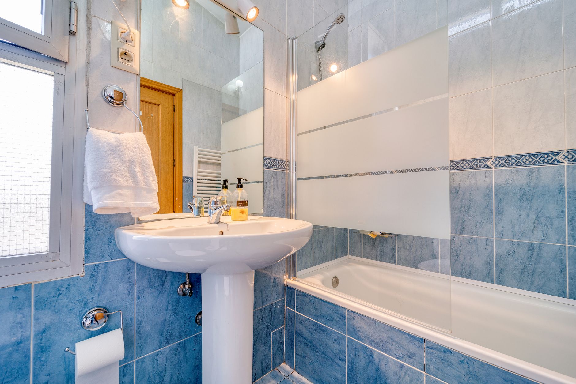 A bathtub with a shower in a bright bathroom