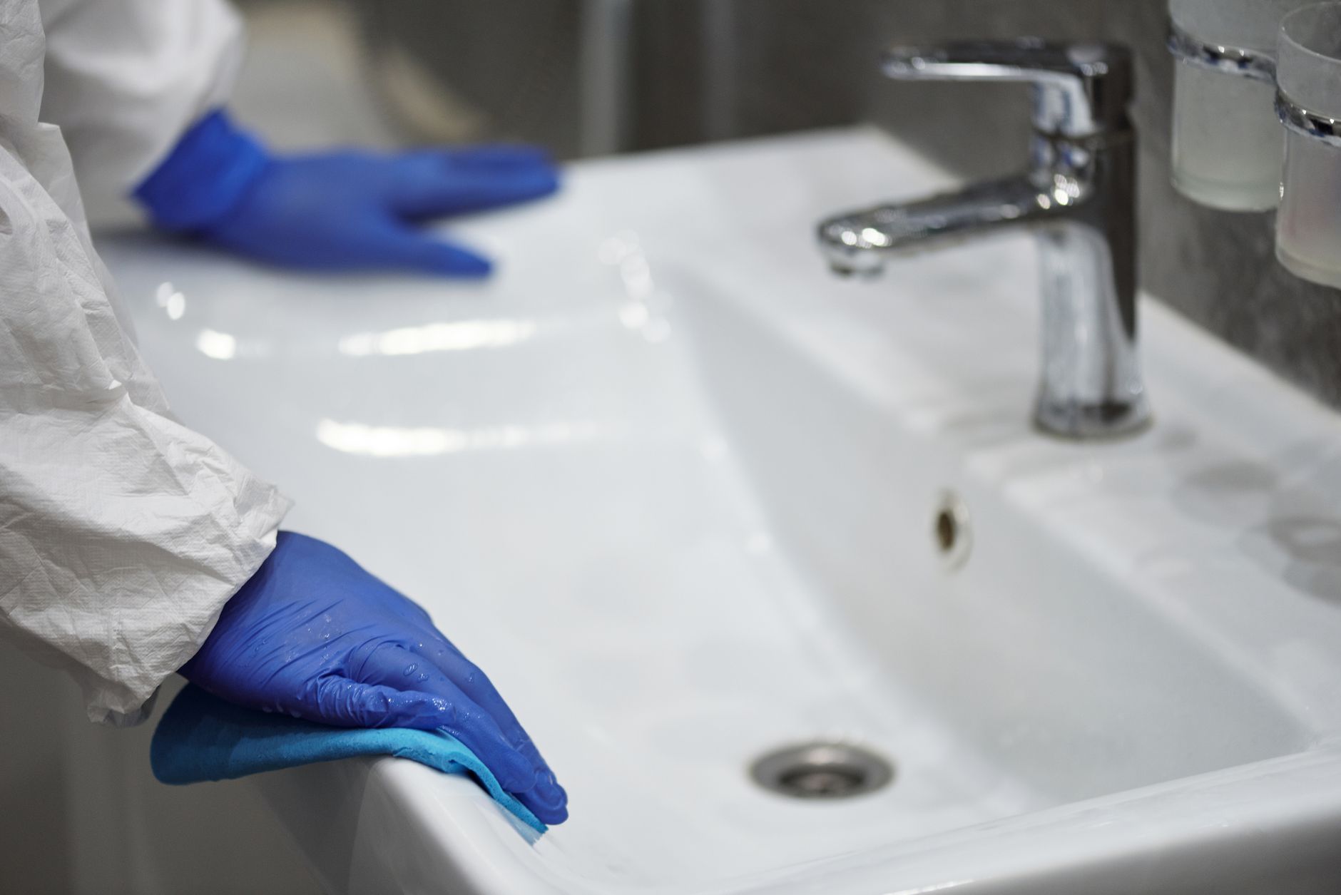 A gloved hand wiping a bathroom sink