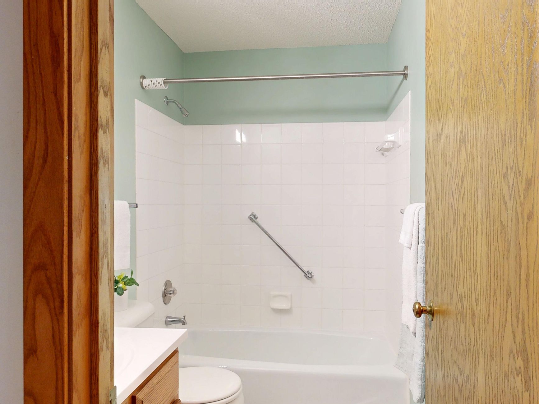 A tub with a grab bar on a tiled wall