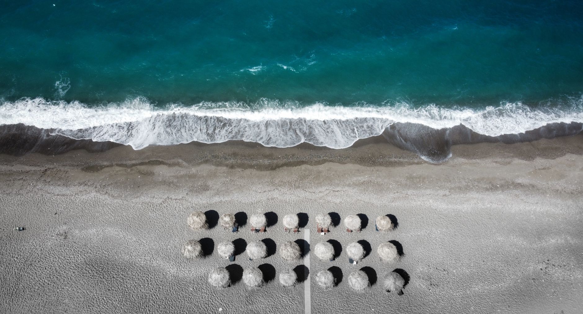 Beach umbrellas lined up near the shoreline