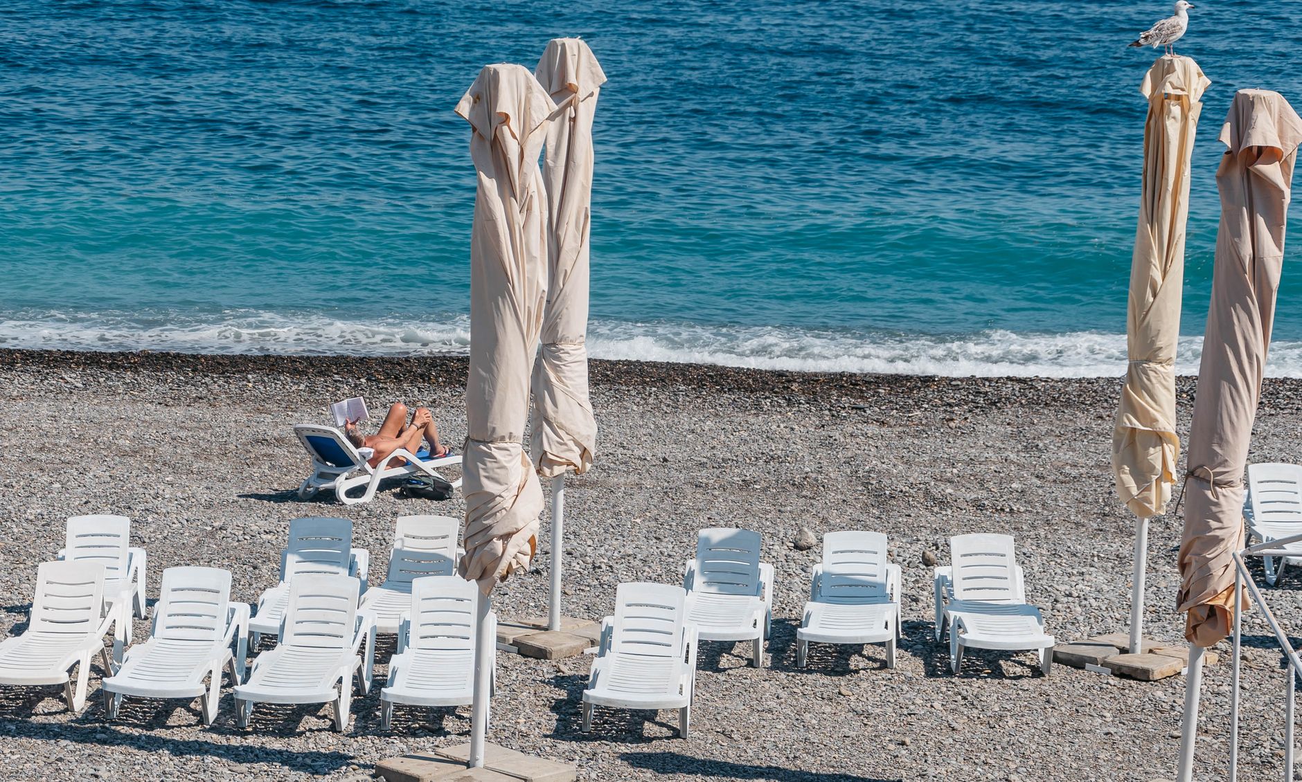 A beach chair in the shade of an umbrella