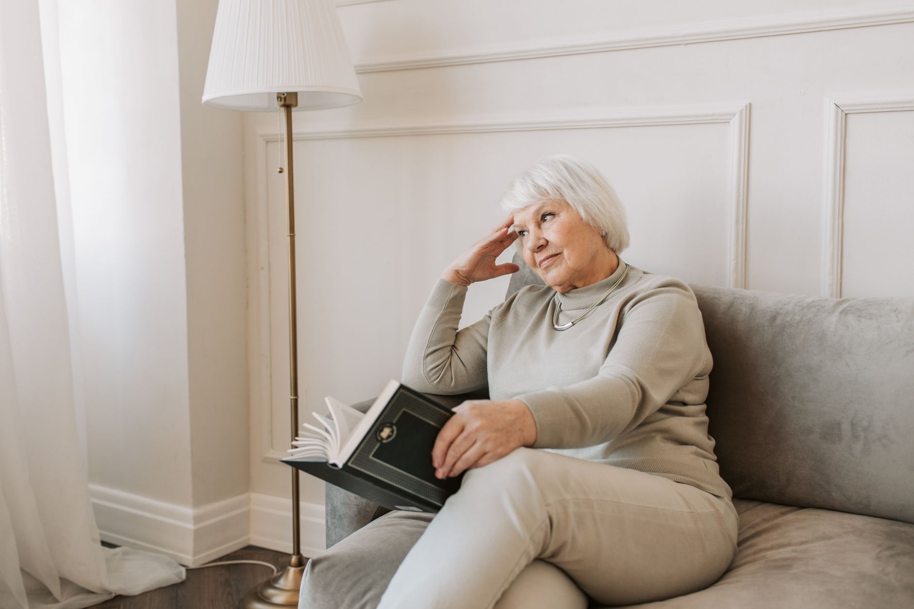 An older woman reading on a sofa