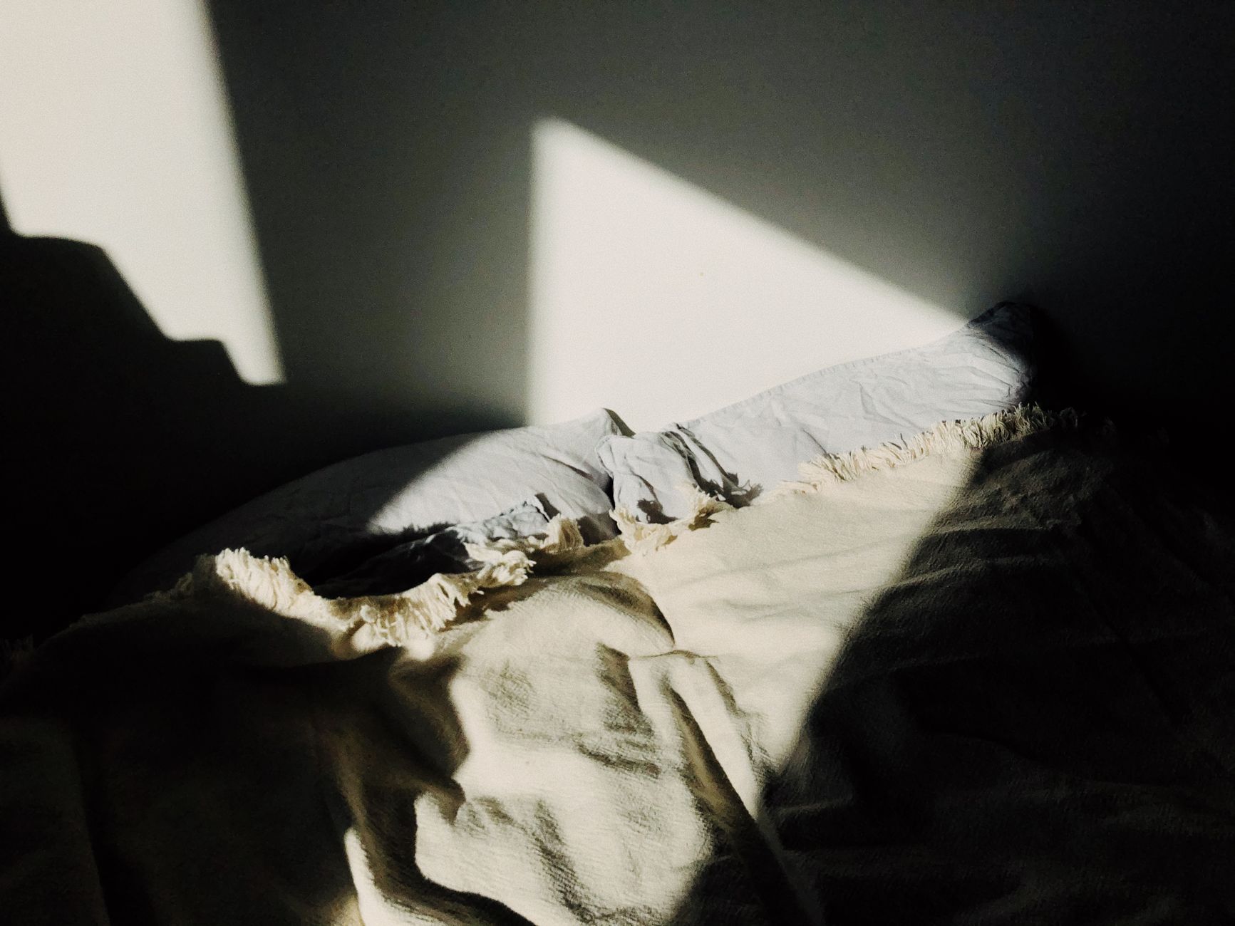 Sunlight falling across an unmade bed