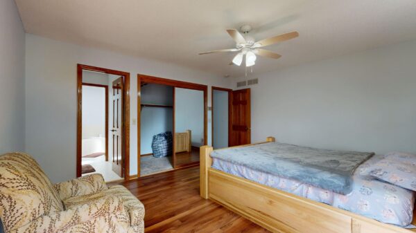 Best bed risers: a wooden bed frame in a bedroom with a ceiling fan