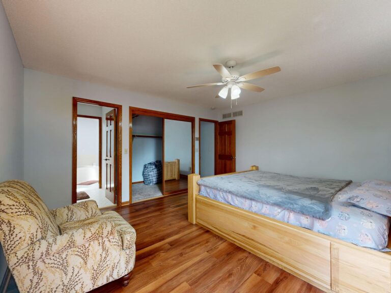 Best bed risers: a wooden bed frame in a bedroom with a ceiling fan