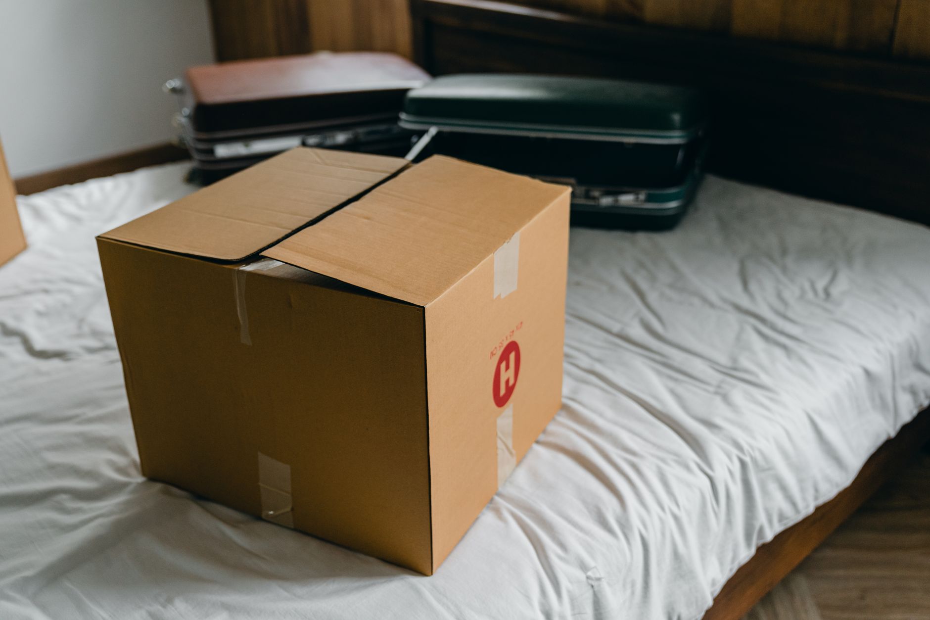 A moving box and suitcases on a bed
