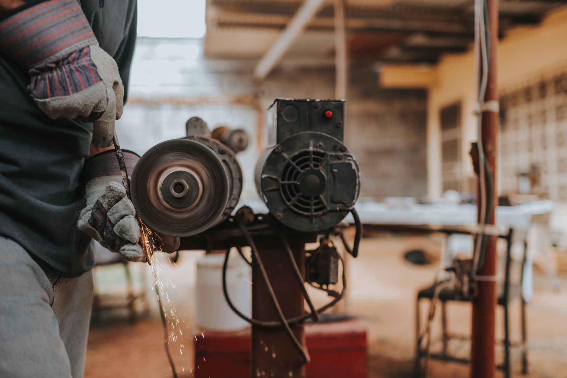 A worker grinding metal at a bench grinder
