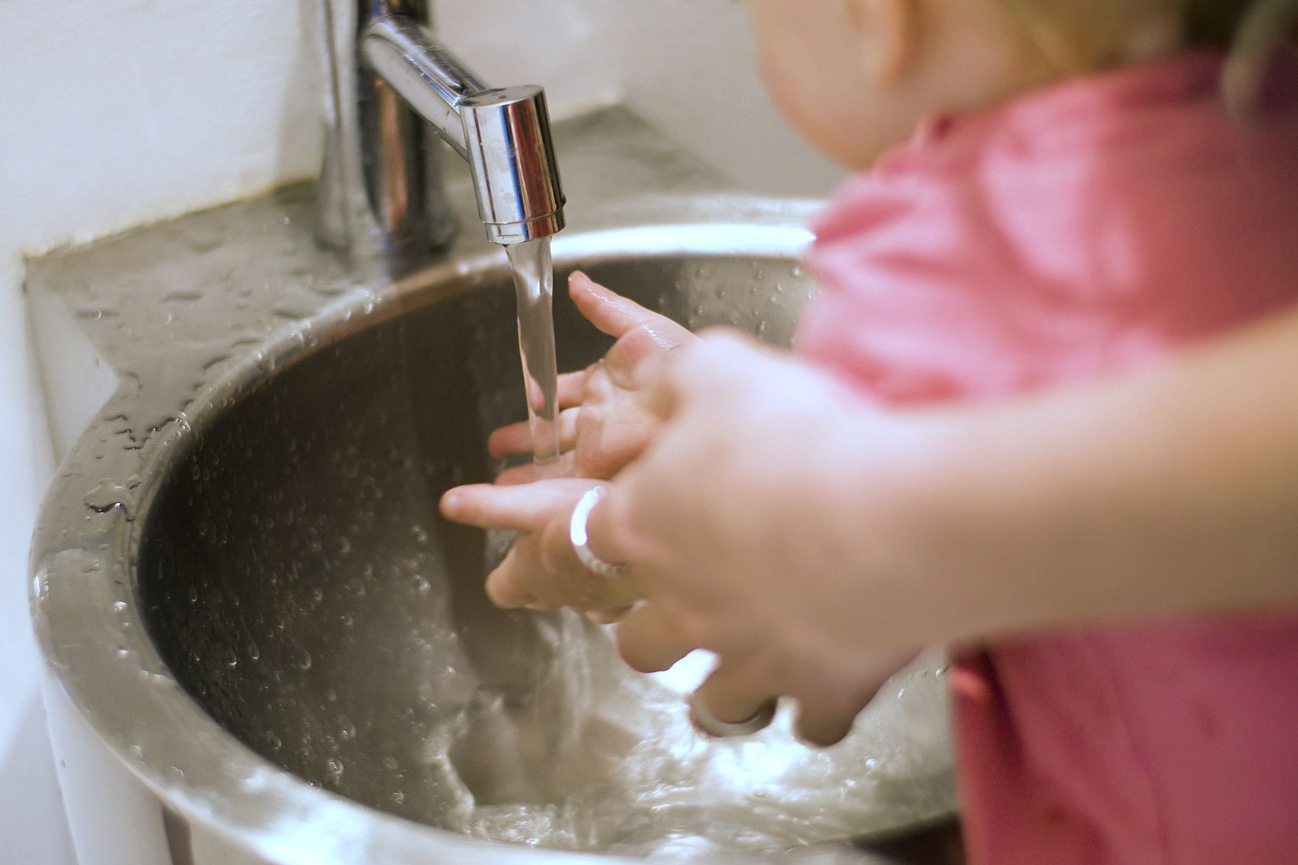 Hands being washed under a bathroom faucet