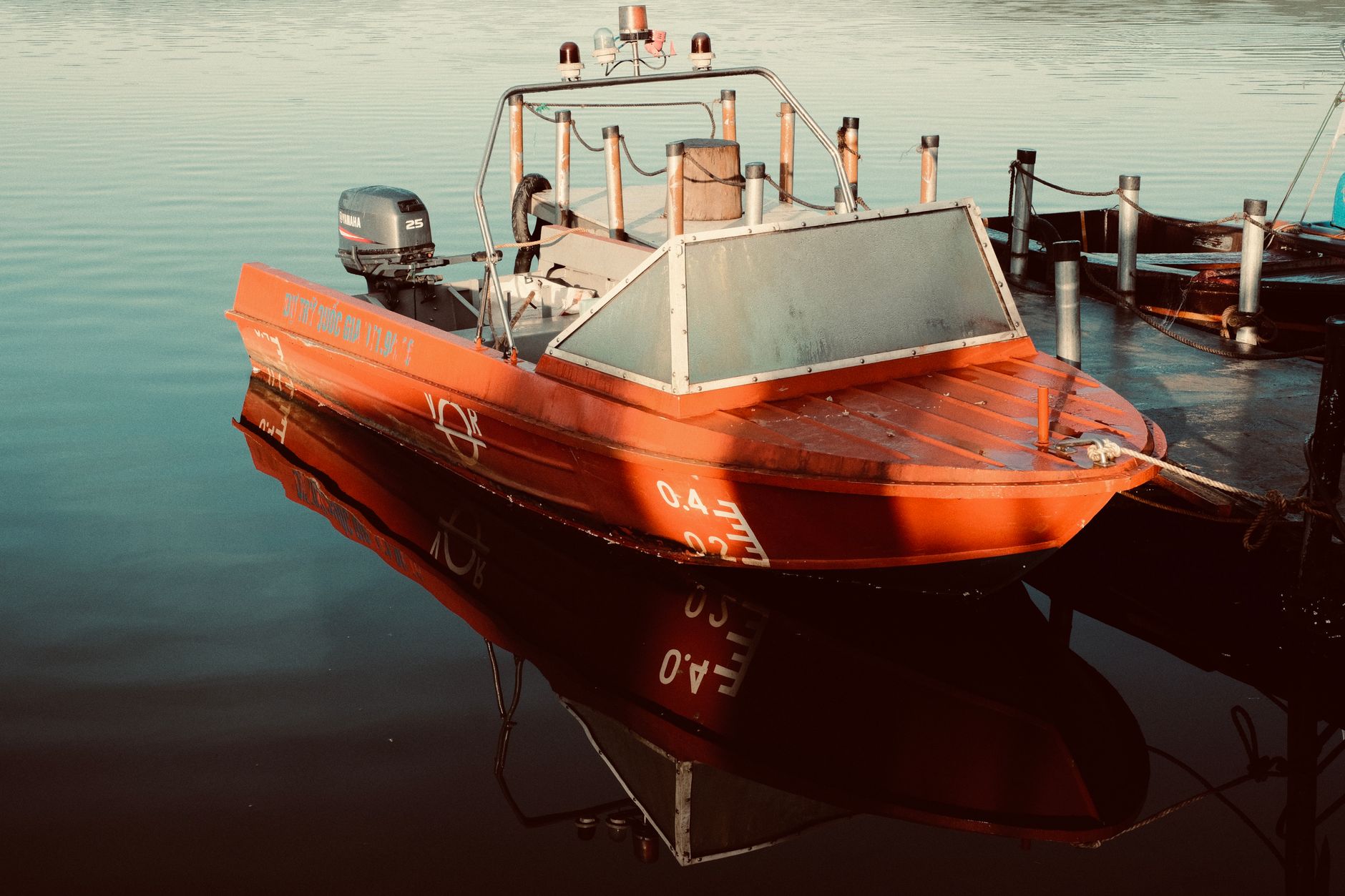 An orange motorboat moored on calm water