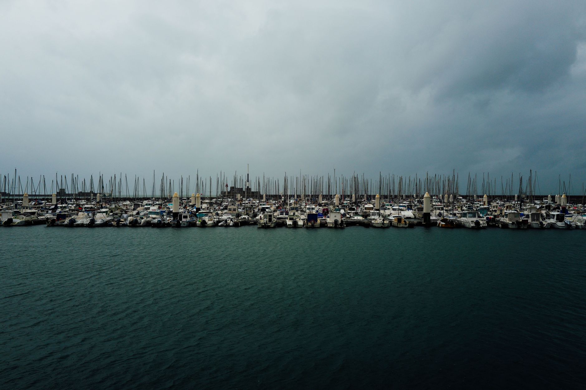 A marina full of sailboats under gray skies