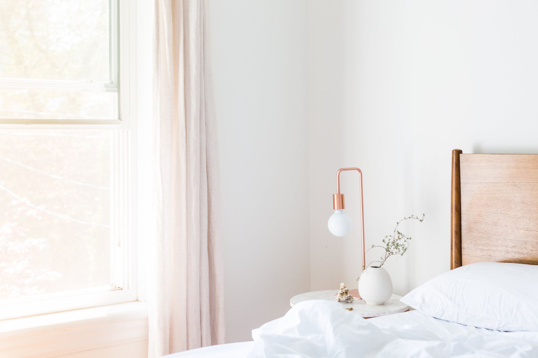 Sheer curtains beside a bed with a lamp