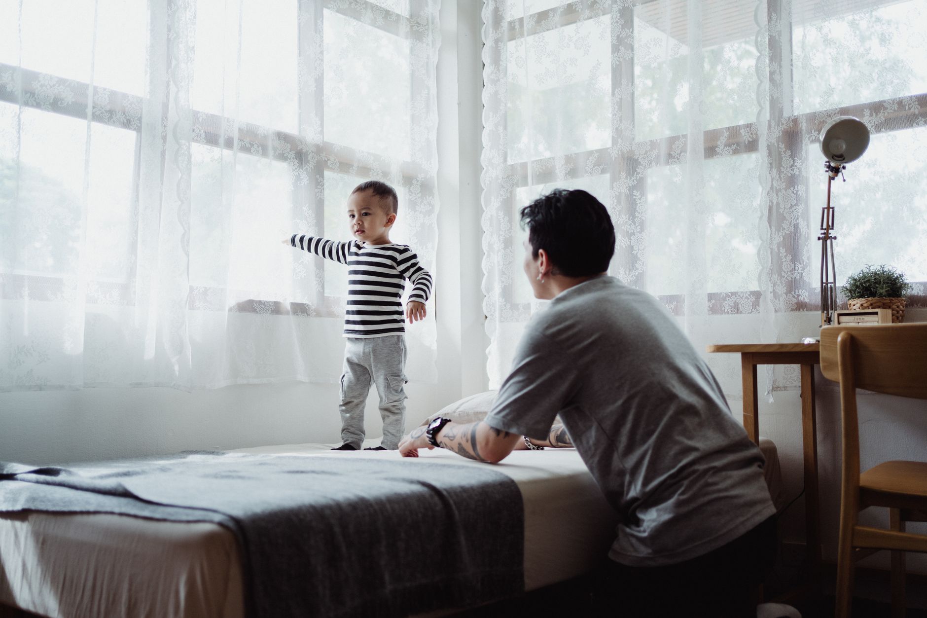 A child standing by a window with a parent