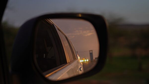 Best blind spot mirror: a car side mirror reflecting the road at dusk