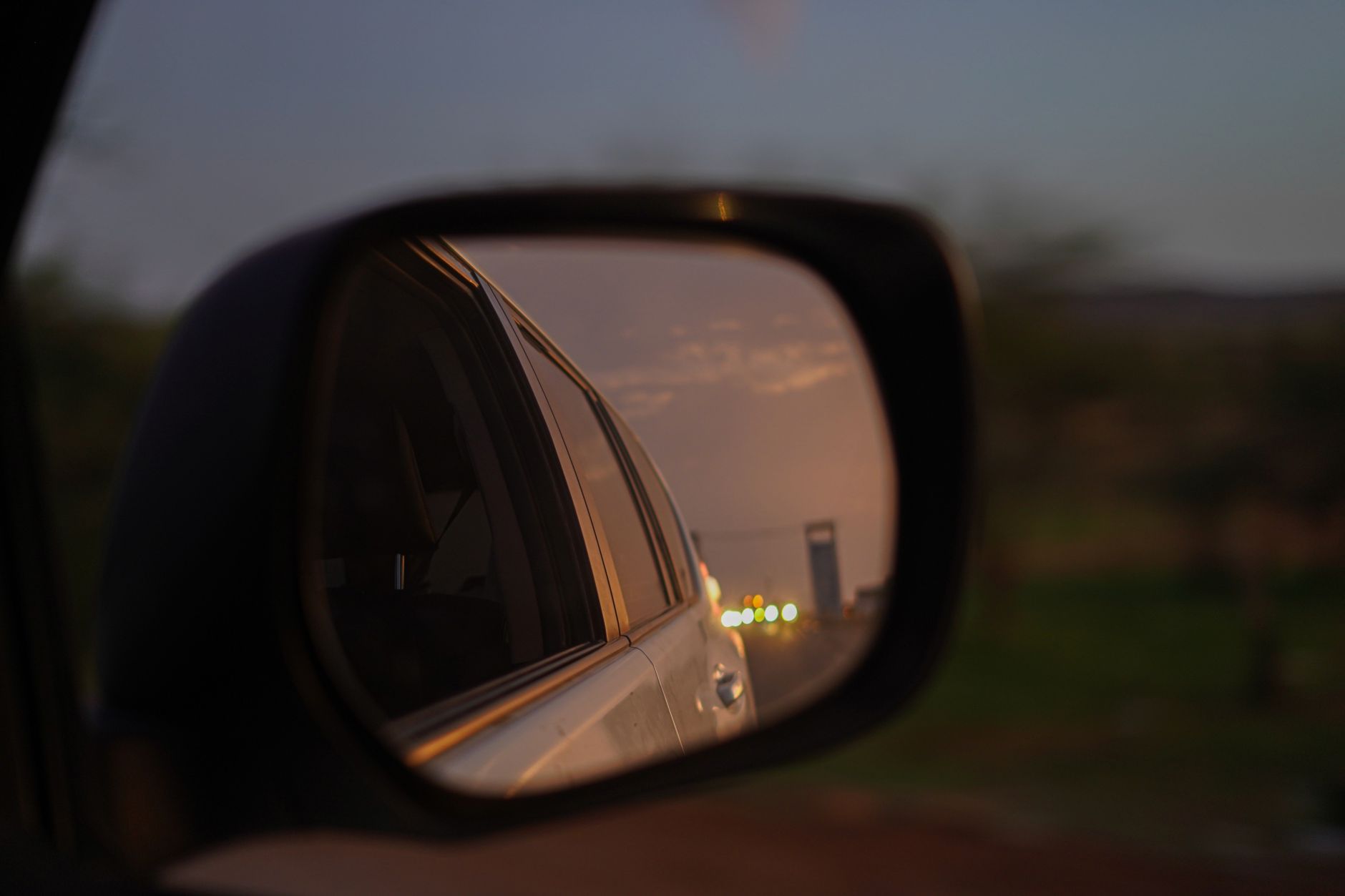 Best blind spot mirror: a car side mirror reflecting the road at dusk