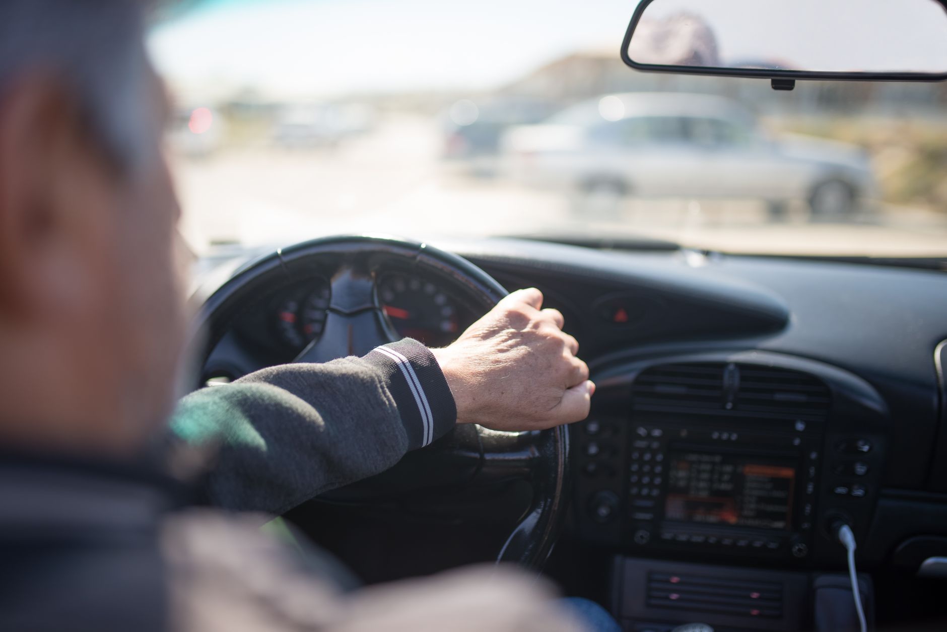 A driver at the wheel looking toward the side mirror