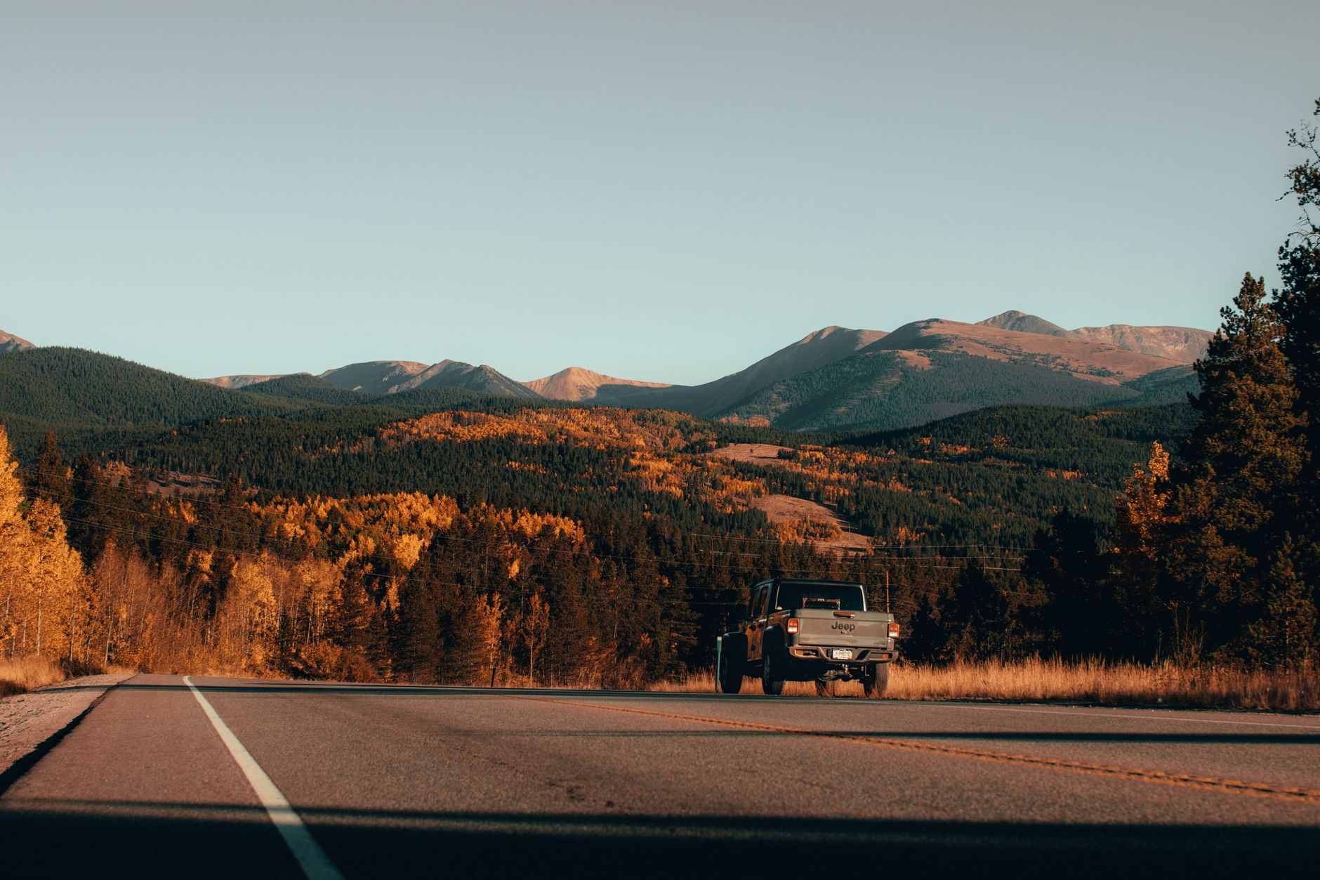 A pickup truck on a road through autumn hills