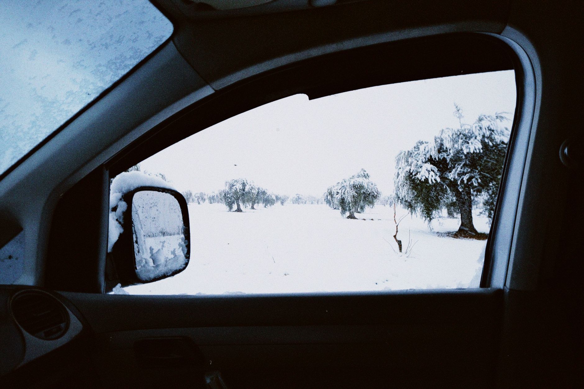 A snowy field seen through a car window