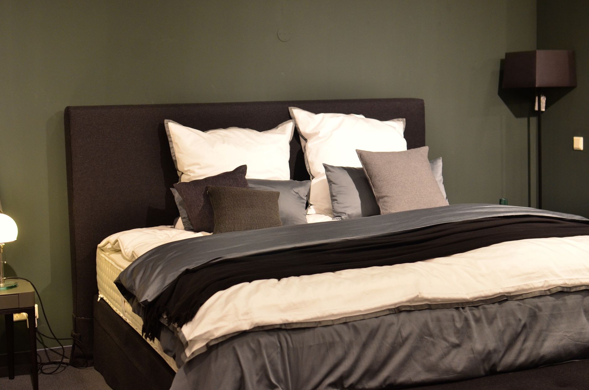 A nightstand beside a bed in a dim bedroom