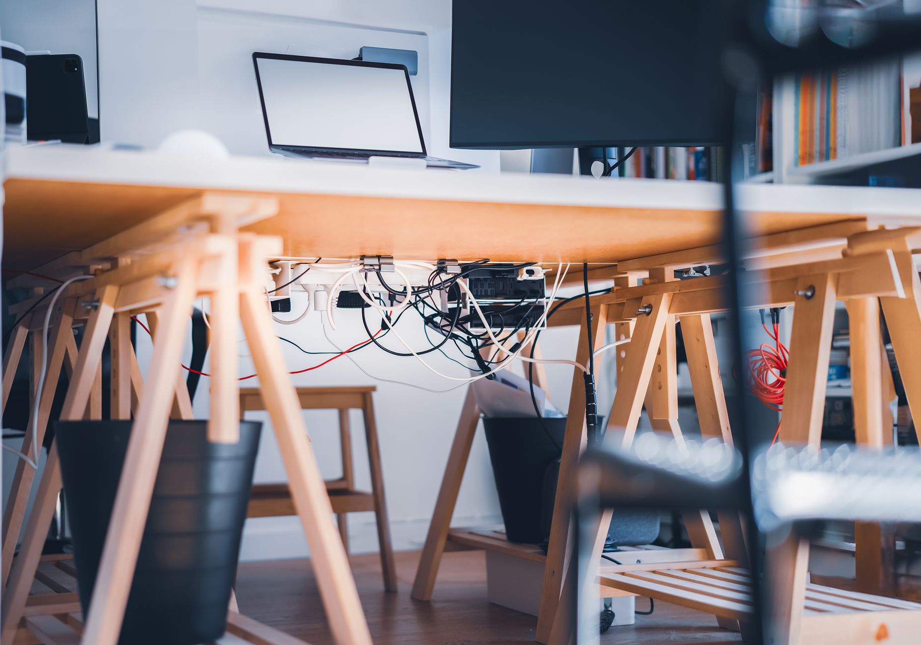 Tangled cables under a trestle desk