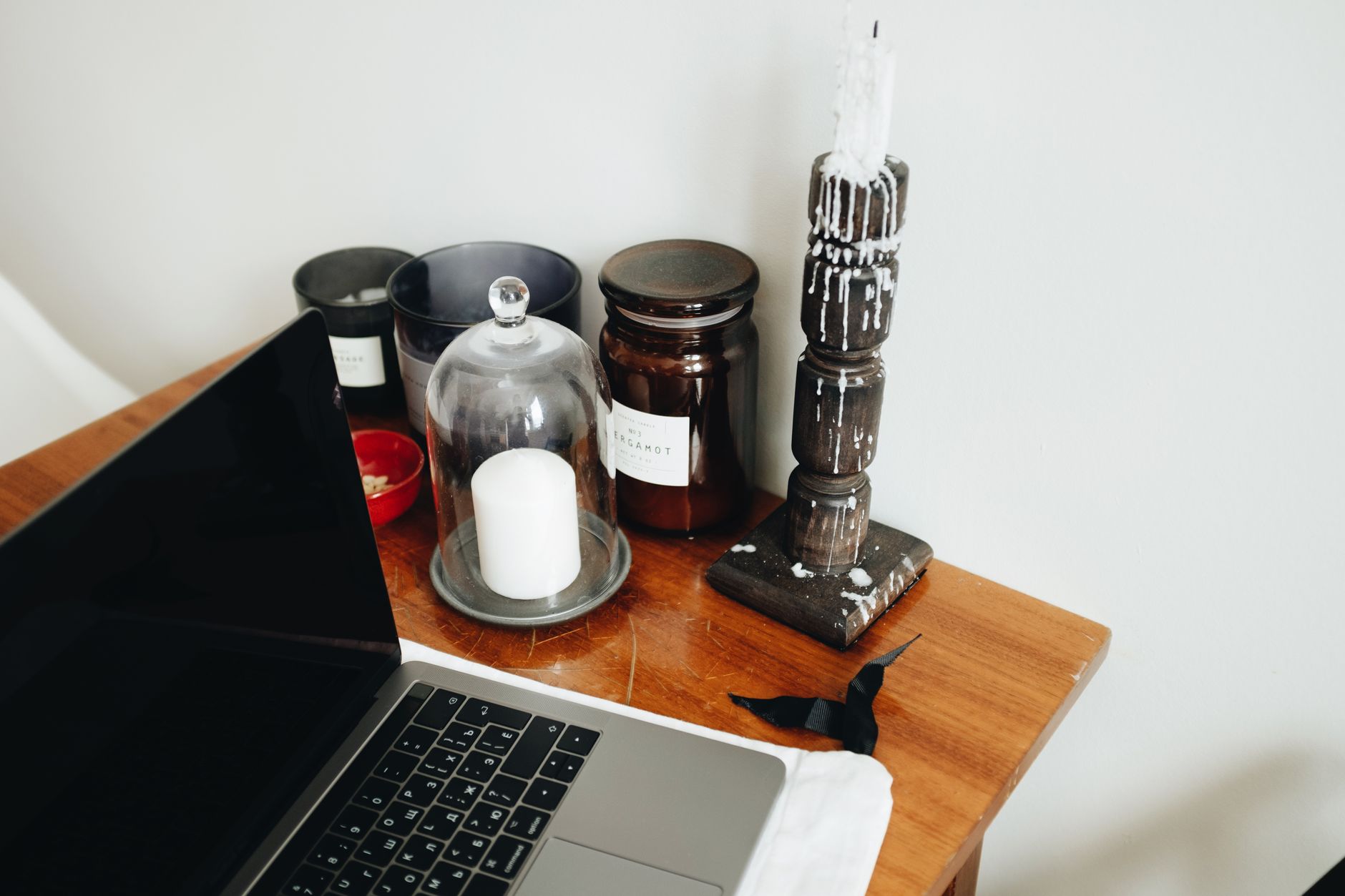 A laptop on a side table with candles