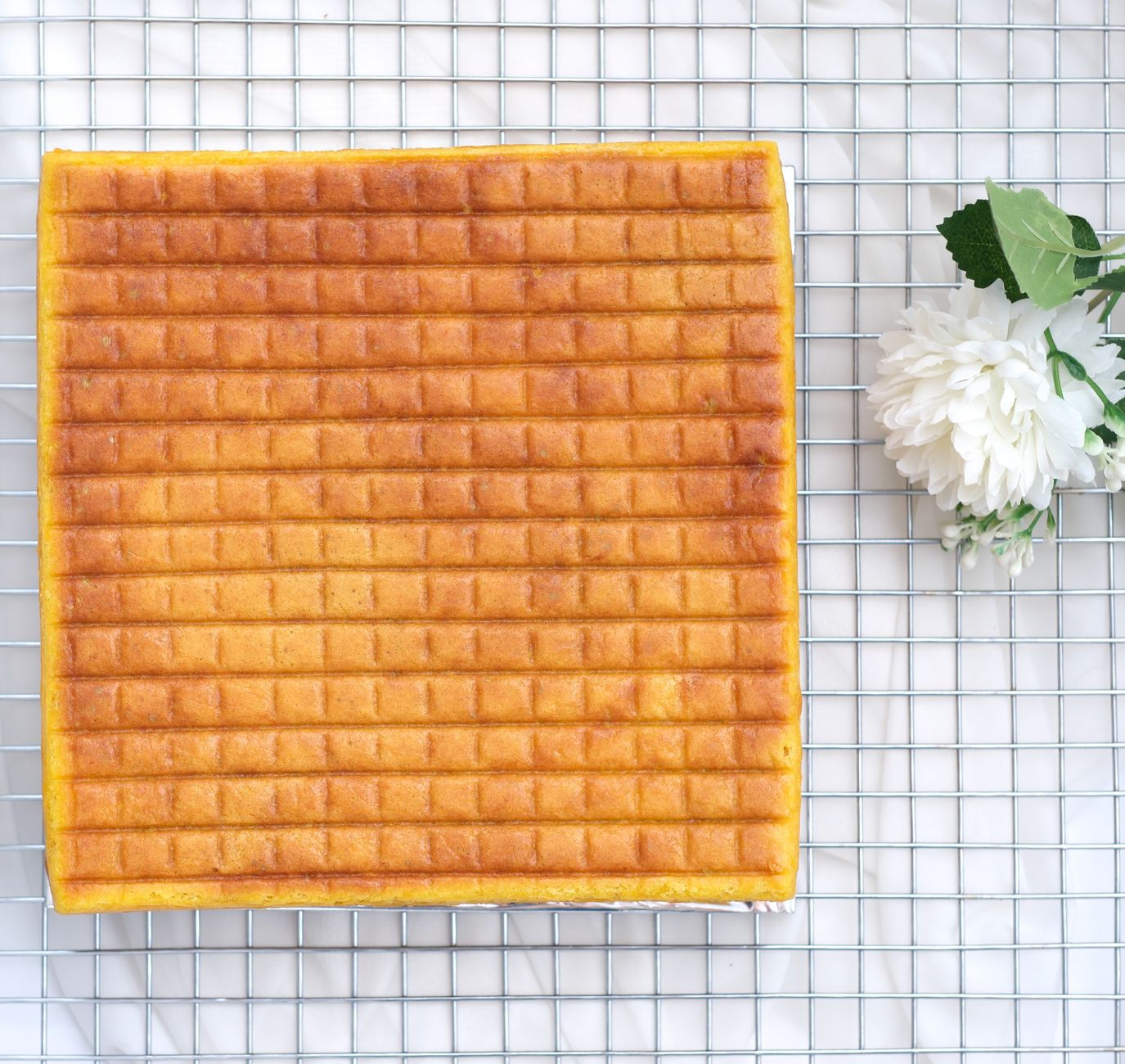 A rectangular cake cooling in a kitchen