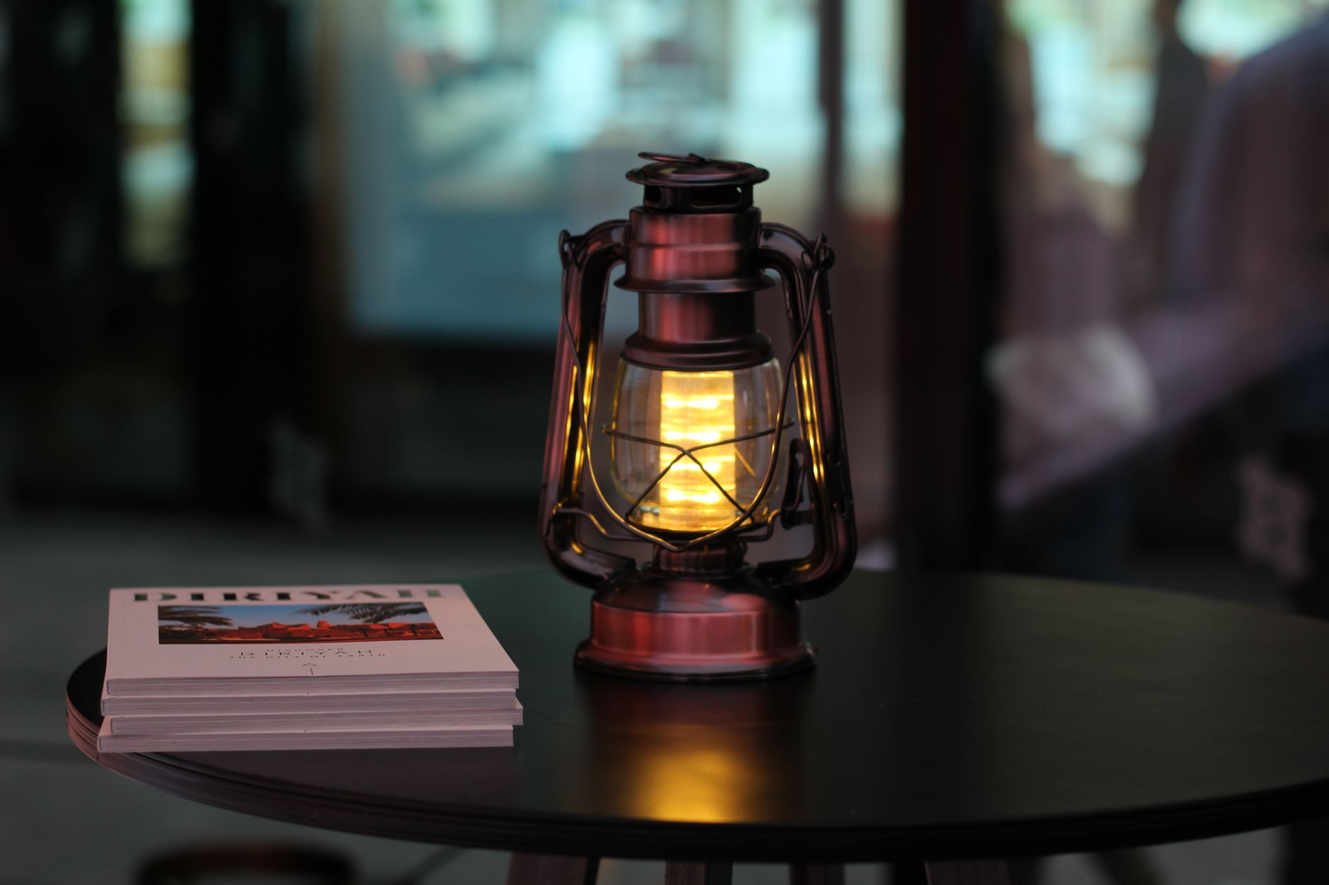 A lantern glowing on a table beside books