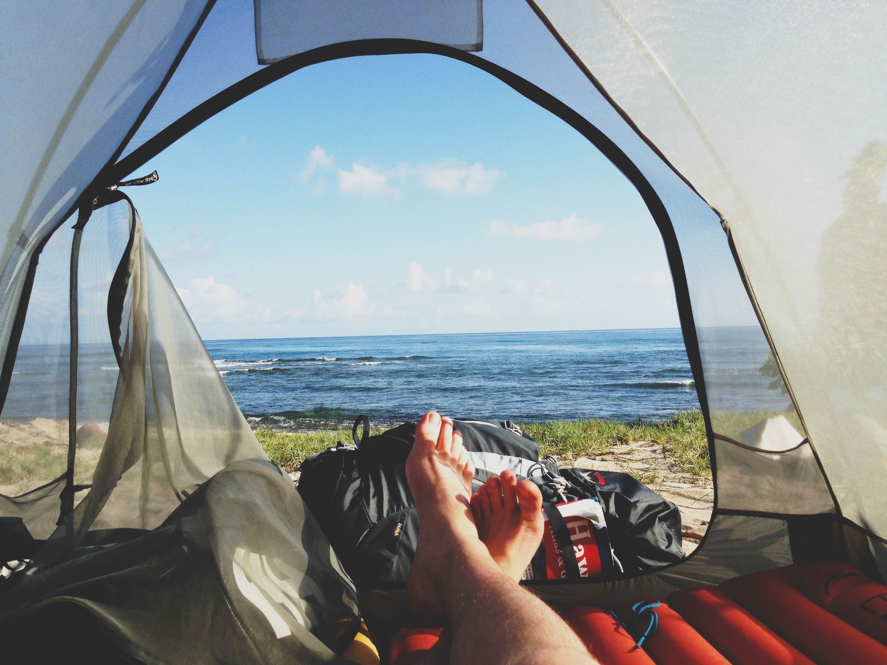 Feet resting inside a tent facing the ocean